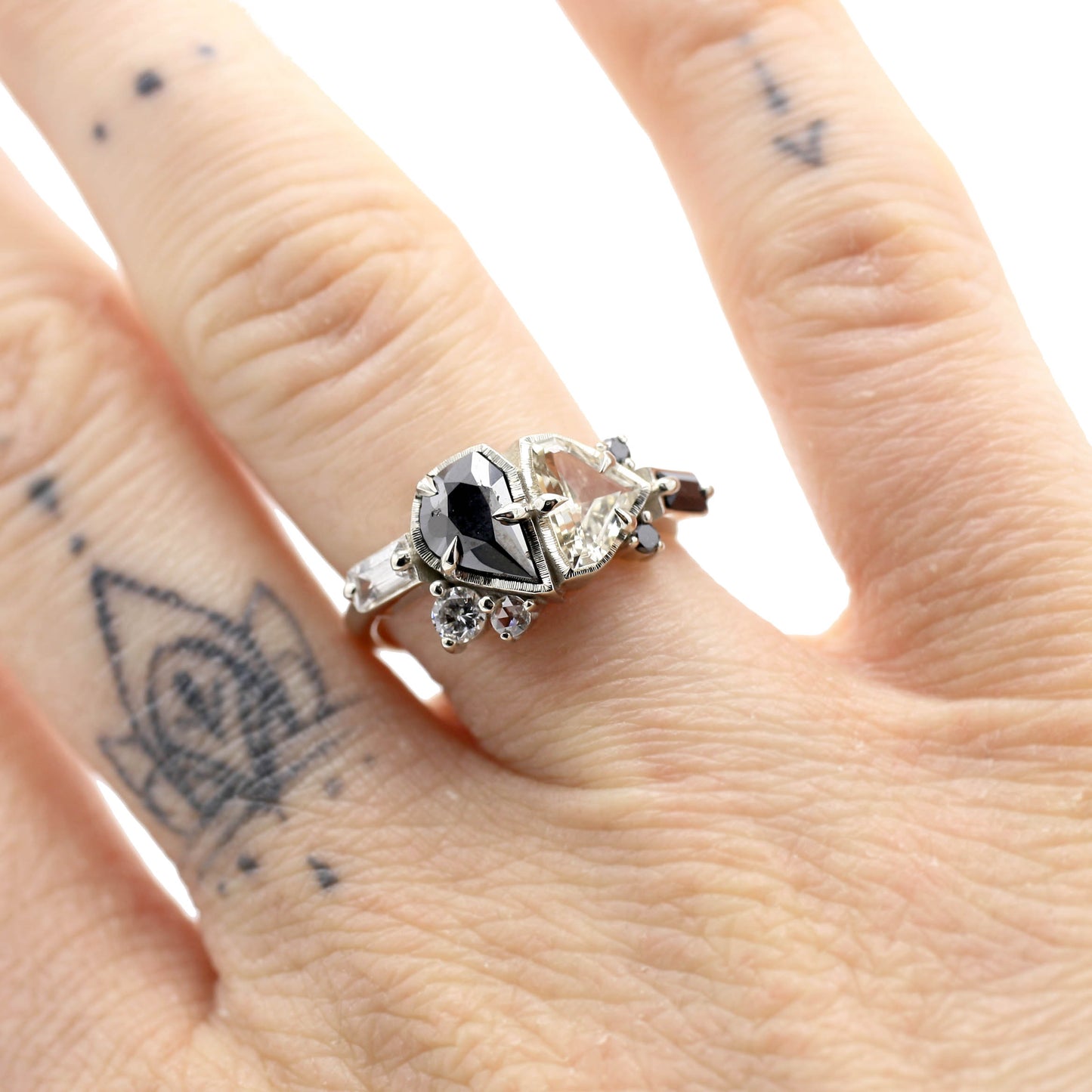 Asymmetric cluster ring with black and white diamonds, sapphires and gemstones on a hand